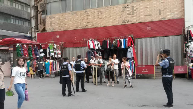 一場「持械」演習結束,烏魯木齊社區警察為後街商販拍照(2018年8月) 一場「持械」演習結束,烏魯木齊社區警察為後街商販拍照(2018年8月)