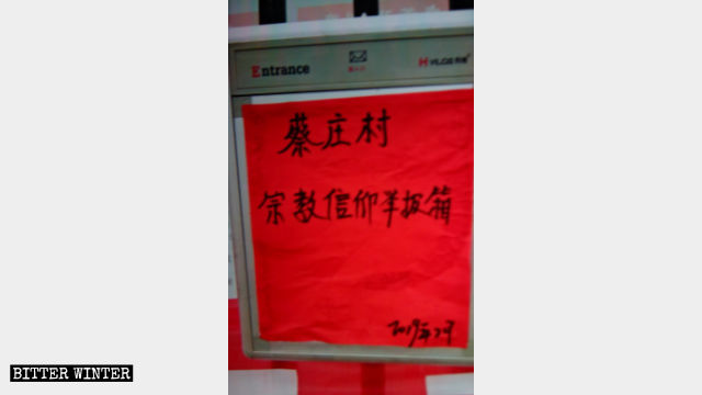 蔡庄村委会墙上挂着一个箱子，上面写着「宗教信仰举报箱」