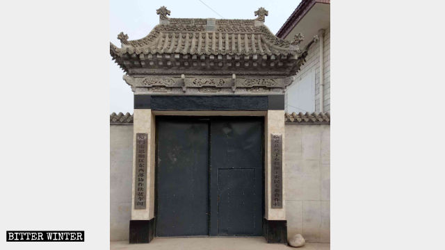 清真东寺的大门被替换为普通的铁门，大门两侧挂着改造後的标牌