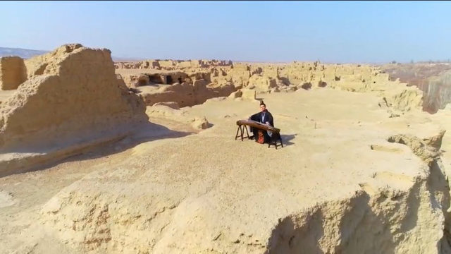 在維吾爾族迎春節活動期間,一位漢族音樂家在吐魯番交河故城的高地上演奏古箏,慶祝春天的開始 在維吾爾族迎春節活動期間,一位漢族音樂家在吐魯番交河故城的高地上演奏古箏,慶祝春天的開始